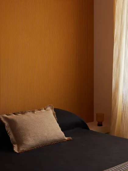 Endless vertical stripes on this wallcovering evoke timeless depth and serenity. The ribbed lines of the 'Colonne' design offer a tactile journey, blending classical elegance with a clean, contemporary aesthetic for a modern bedroom.