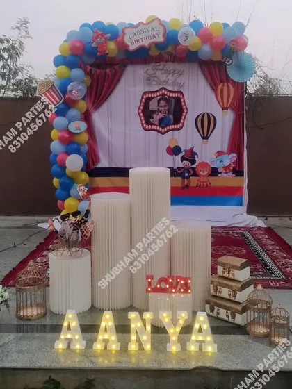 A festive carnival themed outdoor birthday party with a colorful backdrop and props.
