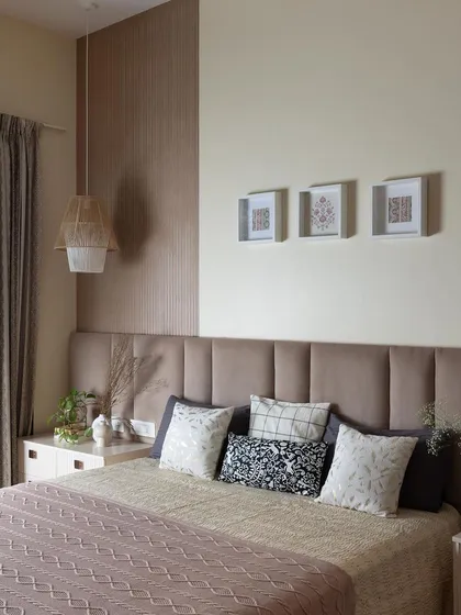 Texture and tranquility define this space. A soft, upholstered headboard is framed by a textured accent wall, creating a subtle yet sophisticated look. The mix of cushions adds another layer of comfort.