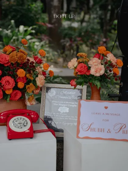 A unique guest book idea for the Rishikesh Haldi. A vintage red telephone is set up for guests to leave audio messages for the couple, combining a nostalgic touch with modern technology.