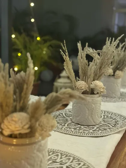 A detailed shot of the boho tablescape, showing the textured vases with dried flowers and the intricate pattern of the table runner. Every element is chosen to contribute to the overall aesthetic.