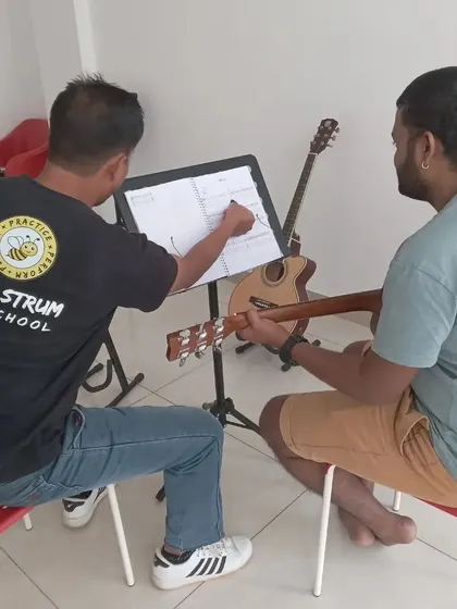 Our instructor pointing out notes on the sheet music during a guitar lesson. We teach music theory alongside practical skills.