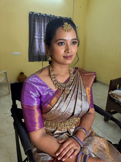 A full-view of Swathy's engagement look. She looks elegant and poised in her purple and silver saree, with her hair styled in a chic updo.