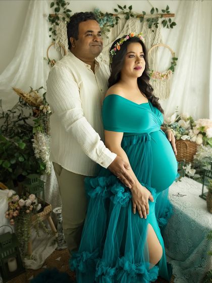 A beautiful couple's portrait from a twin maternity session. The husband stands behind his wife, both looking off-camera with happy, expectant expressions.