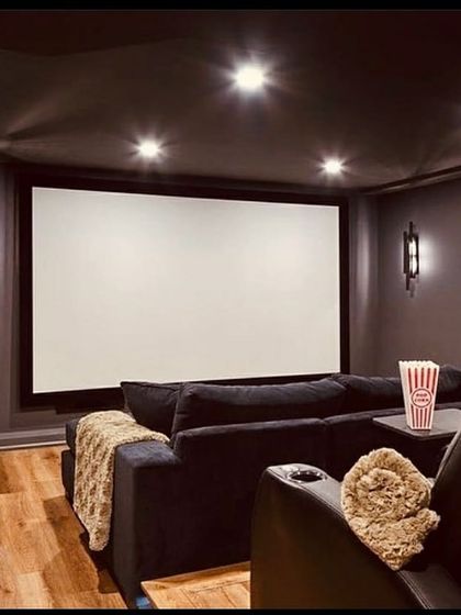 This media room combines the comfort of a deep sofa with the luxury of a dedicated recliner, catering to different viewing preferences. The large screen, classic movie posters, and accessible snack cart create a fun and functional space for family movie nights.