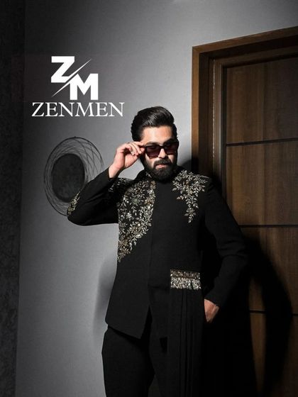A model wearing a black Indo-Western outfit with asymmetrical gold embroidery and a draped detail. A fusion of classic tailoring and modern design.
