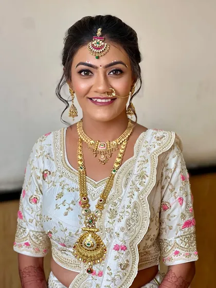 For this bride's day ceremony, we chose an elegant white and gold lehenga. The makeup was kept soft and glowing, with a classic floral bun to create a look that felt both warm and real.