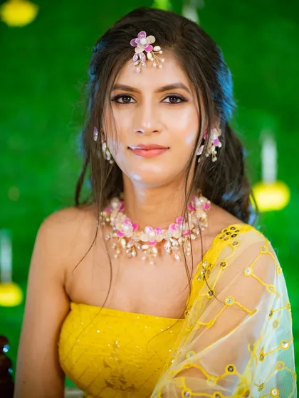 A beautiful portrait of a woman ready for her Haldi ceremony, wearing a yellow outfit and delicate floral jewellery.