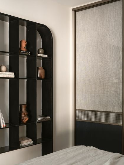 This shot highlights the clever use of materials in the son's room. The black bookshelf stands next to a sleek sliding wardrobe, which features a tartan-inspired fabric as a nod to the client's time in Scotland.