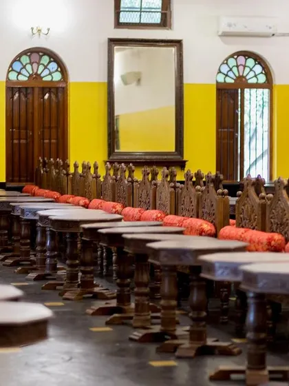 The dining hall, set up with traditional wooden stools for a sadhya feast or other traditional meals.