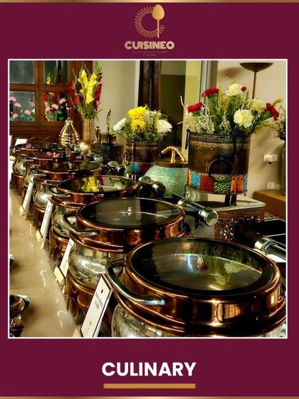 A row of our signature copper-lidded serving pots, keeping the main courses hot and ready. The floral arrangements add a fresh, decorative touch to the culinary display.