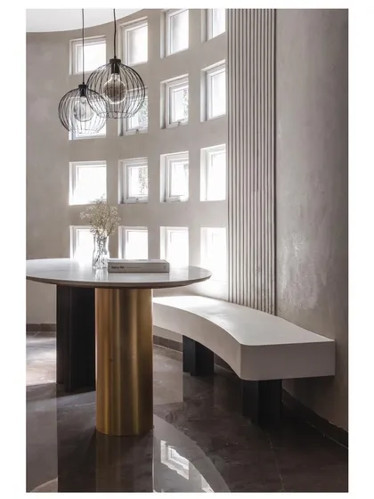 In our 'House Under Tabebuia Trees' project, we designed this dining nook as a sanctuary of light. The curved wall with a grid of windows floods the space with diffused natural light, while the custom-built concrete bench and minimalist furniture create a serene, almost sculptural experience.