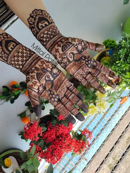 A beautiful shot of a traditional mehndi design against a floral background, highlighting the peacock and elephant motifs.