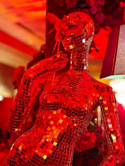 This masquerade-themed party was drenched in dramatic red lighting, with intricate floral centerpieces, candelabras, and even a mirrored mannequin adding to the mysterious and glamorous vibe.