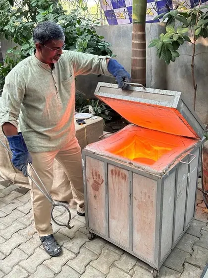 I am opening the glowing hot Raku kiln, ready to remove the pottery. This is a critical moment in the dramatic and fast-paced firing process.