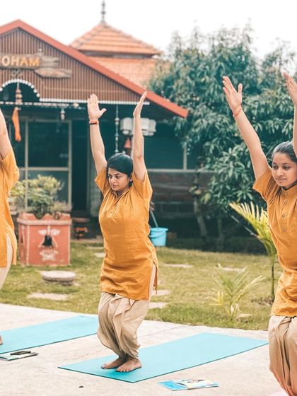 From our yoga shala, you can see students practicing Ardha Uttanasana (Half Standing Forward Bend) in the garden. The serene backdrop of mango trees and open sky makes every practice a communion with nature.