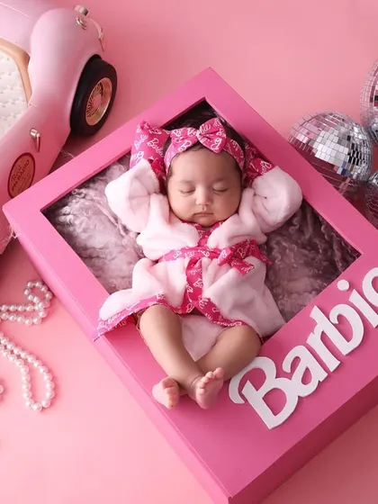 The complete Barbie dream. This shot shows the full setup, with the newborn sleeping peacefully in a "Barbie box" prop. It's a creative and modern theme for parents looking for something unique.