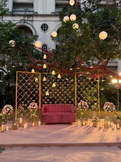 For this outdoor reception, I created a romantic seating area under the stars. The setup features a plush pink sofa against a golden lattice backdrop, surrounded by glowing candles and hanging paper lanterns that cast a warm, magical light. This design shows how I can transform an open lawn into an intimate and enchanting space for your special moments.