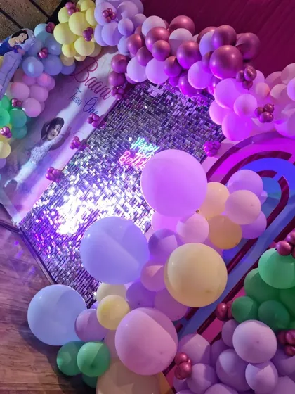 A closer view of a princess-themed party, showing the pastel balloon decorations and the sequin wall that creates a sparkling effect.