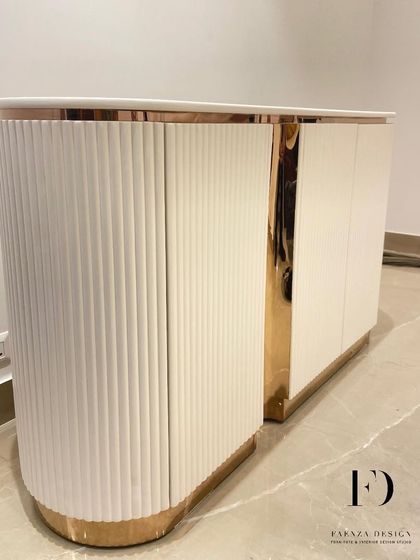 A beautiful custom console designed for a foyer. This piece features a curved, fluted body in a white Duco finish, accented with a rose-gold metallic finish, creating a warm and welcoming first impression.