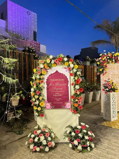 A custom welcome sign for a Maa Bhagwati Jagran, framed by a vibrant arch of multi colored flowers. This is how we greet your guests and set a festive, devotional tone from the very beginning.