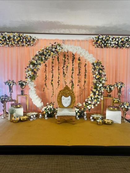 A full view of the stage decor for a half-saree function, showing the balance and scale of the floral arch against the soft curtain backdrop.