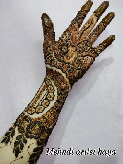 The full design, with the henna paste still on, showing the contrast between the dark paste and the skin. This piece combines bracelet and hand jewelry concepts.