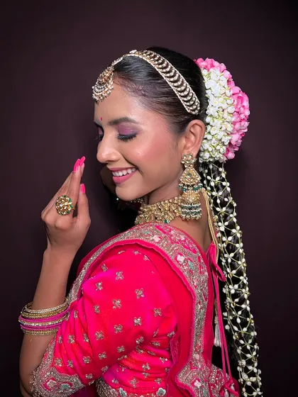A side profile highlighting the long, decorated braid and the glowing makeup.
