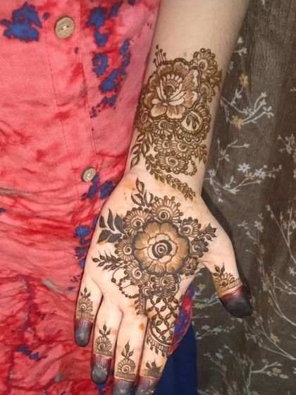A single hand showcasing a beautiful floral and paisley design. The intricate details and shading demonstrate the artistry that goes into even smaller mehendi patterns.