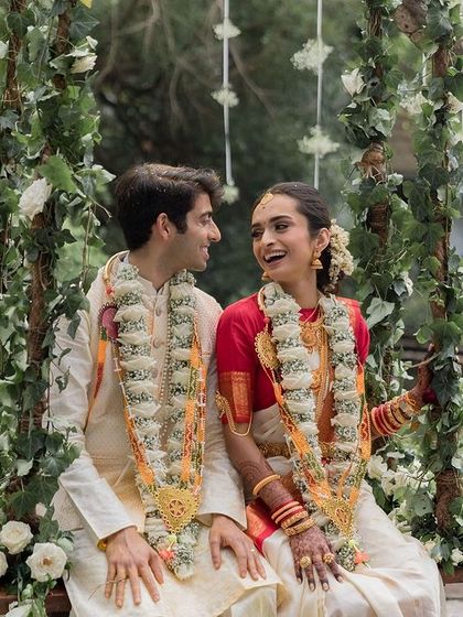 A couple sits on the floral swing by the pond, a classic and romantic shot that captures the essence of a Tamarind Tree wedding.