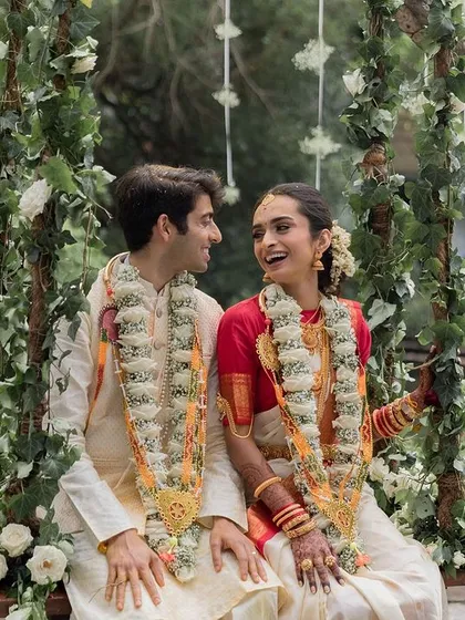 A beautiful NRI couple on the swing, blending Telugu and North Indian traditions in their attire and creating a joyful, vibrant image.