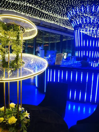 A modern, illuminated centerpiece on a dining table, with the glowing blue bar and starlit ceiling creating a stunning backdrop.