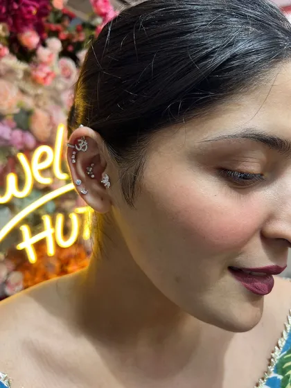 A spiritual and stylish ear curation featuring a sparkling Om symbol, butterfly studs, and other delicate pieces that reflect a beautiful inner peace.