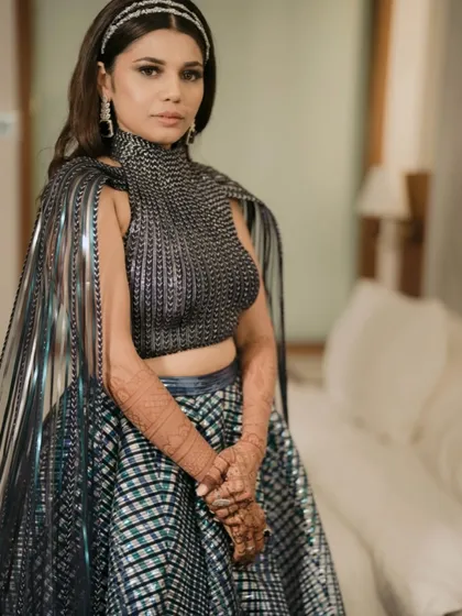 The bride looks powerful and elegant in her metallic outfit, with her hair styled in simple waves to balance the dramatic look.