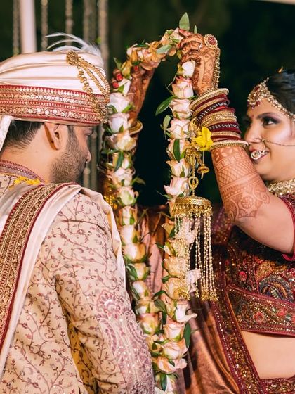 The bride playfully places the varmala on the groom, a fun and candid moment during the wedding ceremony.
