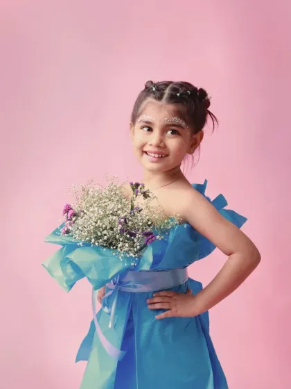 A fashion-forward portrait with a dress made of paper and a bouquet of flowers. This creative concept shows off her confident and stylish personality.