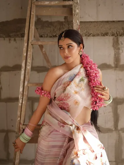A profile shot showing the elegant drape of the saree and the long braid adorned with flowers. This angle highlights the hairstyle and the clean lines of the look.