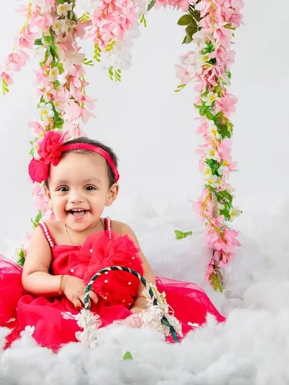 A sweet smile from the birthday girl, holding a basket in her dreamy, floral-themed first birthday shoot.