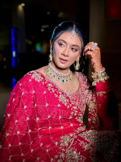 A regal pose from the bride. The makeup features a soft pink and gold eyeshadow look, paired with a subtle pink lip to complement her outfit.