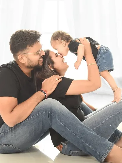 Another angle of a playful family moment, with the mother lifting her child up for a kiss. The high-key lighting and simple setting keep the focus on the emotion and action.