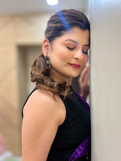 A serene, eyes-closed shot showing the details of the eye makeup. The soft blend of colors and the neat ponytail create a very chic and polished look.