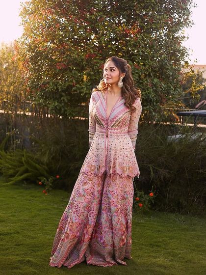 A beautiful outdoor shot showcasing the full Tarun Tahiliani outfit and the fresh, event-ready makeup.