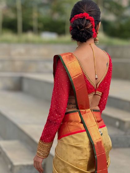 The back view of a red net blouse with full-length sleeves. The sheer fabric is dotted with delicate embroidery, and the deep V-back adds a touch of modern allure to the traditional silhouette.