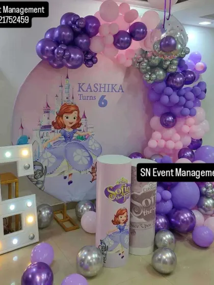 A royal celebration with a Sofia the First theme for a 6th birthday. This setup includes a castle backdrop, a large light-up number '6', and a beautiful balloon arrangement in shades of purple and pink.