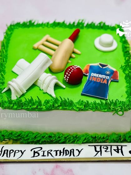 A perfect cake for any cricket lover. This square cake looks like a cricket pitch, complete with a fondant bat, ball, stumps, and an Indian team jersey.