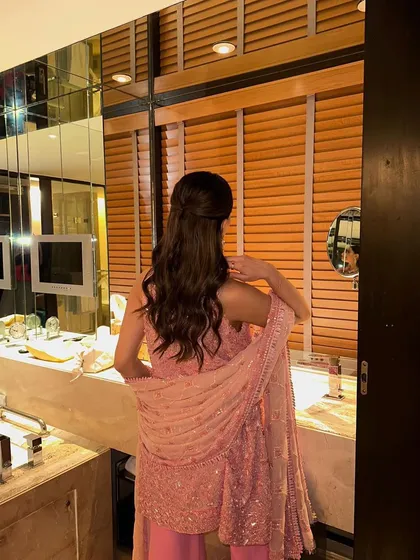 A behind-the-scenes shot of the final look. The half-up hairstyle with soft waves at the end is a perfect complement to the shimmering pink outfit.