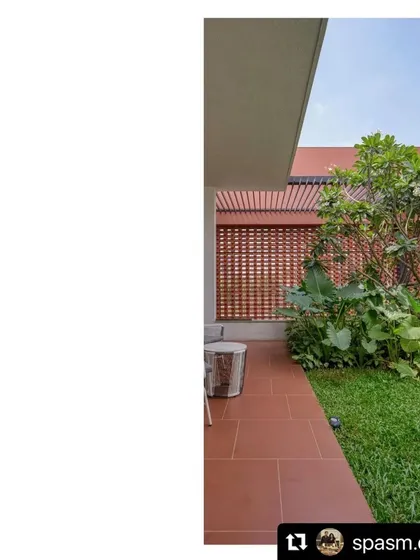 A quiet patio at the Ishtika house, where the interior opens onto a private lawn. The space is screened by a brick jali wall and lush planting, creating a perfect spot for morning coffee.