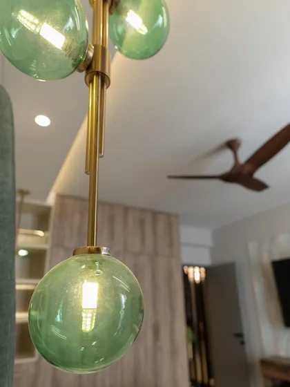 Another angle of the green glass pendant, showing how it contrasts beautifully with the warm wood tones of the fan and wardrobe in the background.