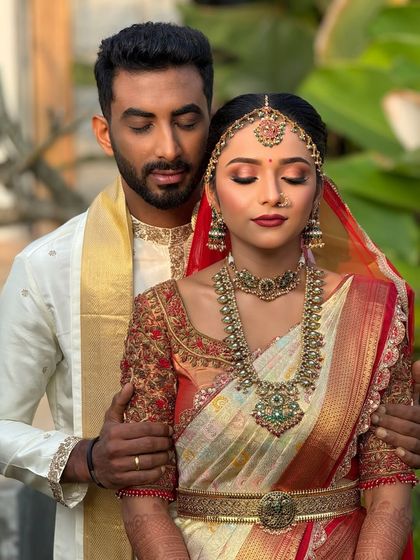 A beautiful moment between the bride and groom. Her makeup, featuring soft eyeshadow and a classic red lip, complements her traditional attire perfectly.