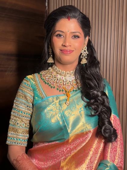 The refined elegance of a reception look. We chose soft curls, luminous skin, and a dewy touch to complement her beautiful turquoise and gold saree.